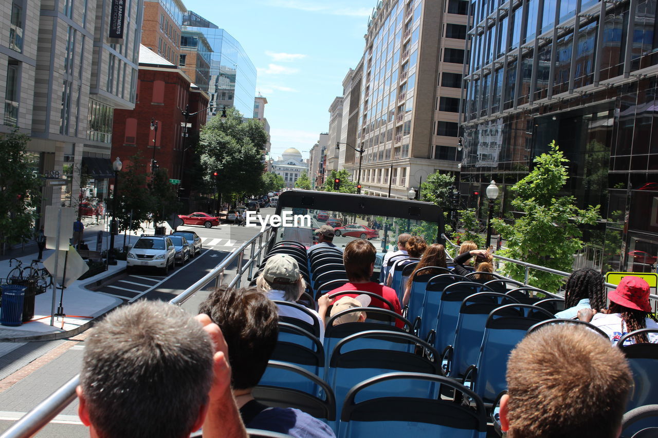 Rear view of people sitting on tour bus in city