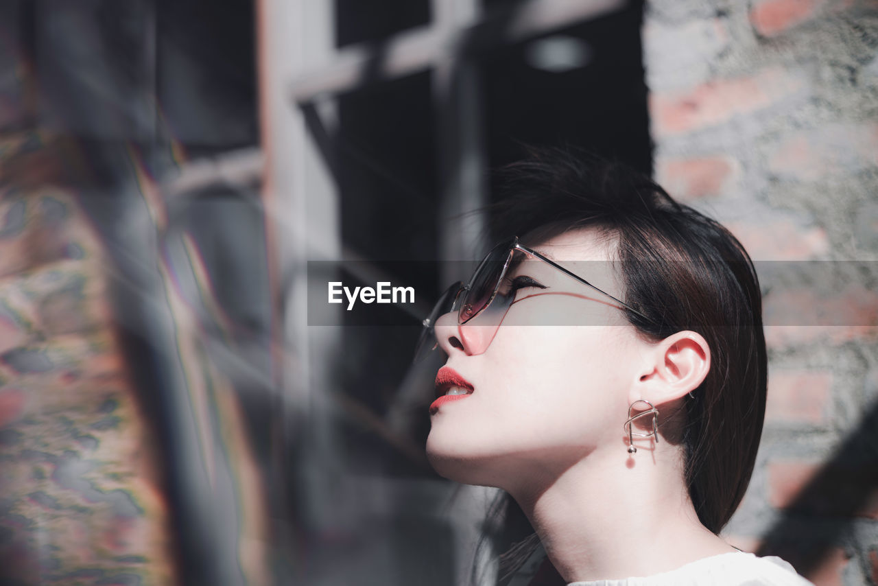 Close-up of beautiful woman wearing sunglasses while looking away
