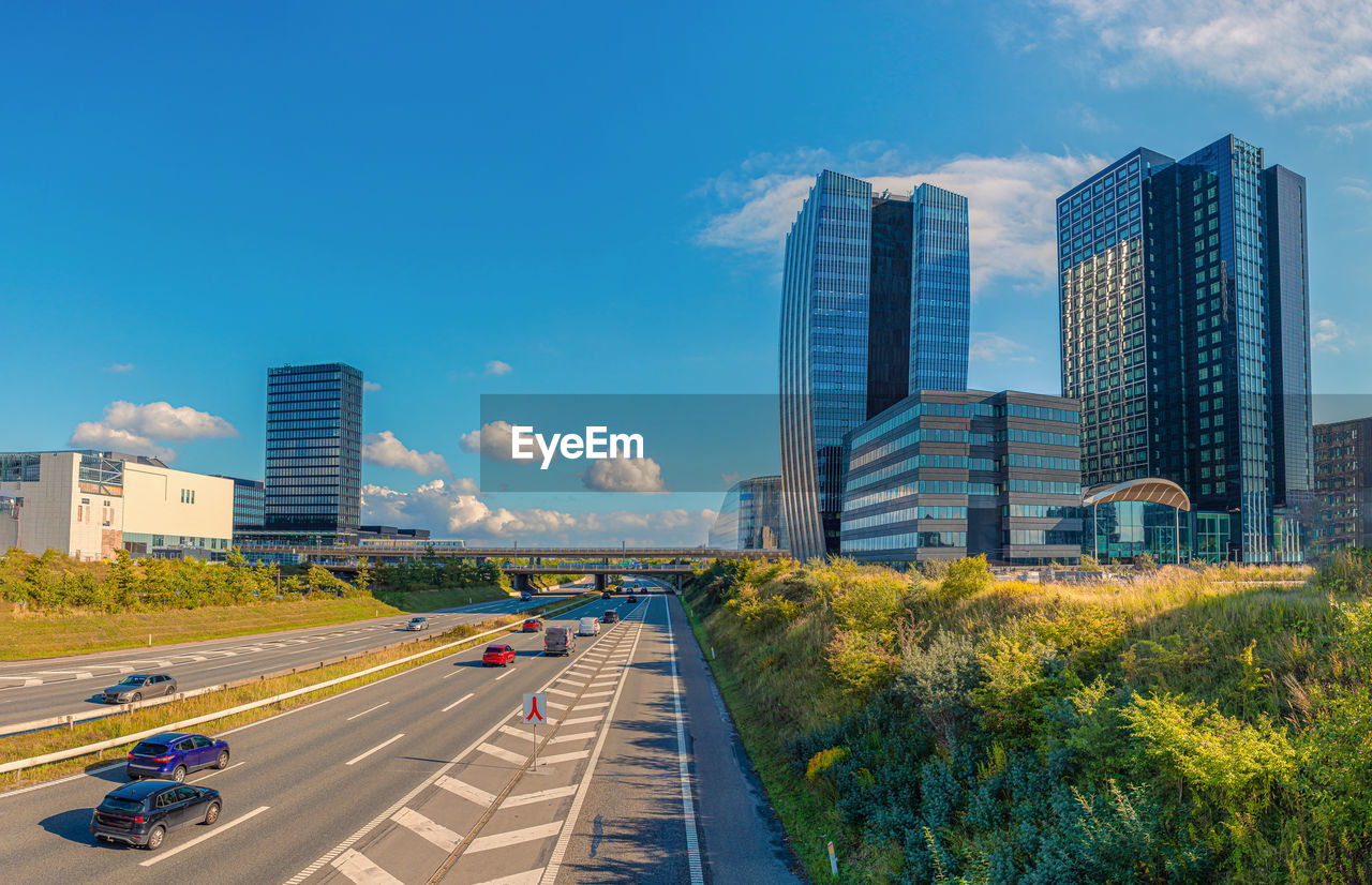 architecture, city, built structure, building exterior, office building exterior, skyscraper, building, transportation, sky, metropolitan area, skyline, cityscape, road, landscape, urban skyline, street, horizon, mode of transportation, nature, motor vehicle, urban area, car, city life, downtown district, highway, downtown, residential district, office, traffic, tower block, city street, travel, travel destinations, landmark, blue, residential area, outdoors, no people, plant, business, cloud, motion, day, high angle view, metropolis, sunlight, development, financial district, symbol, tower, urban road, land vehicle, business finance and industry, freeway