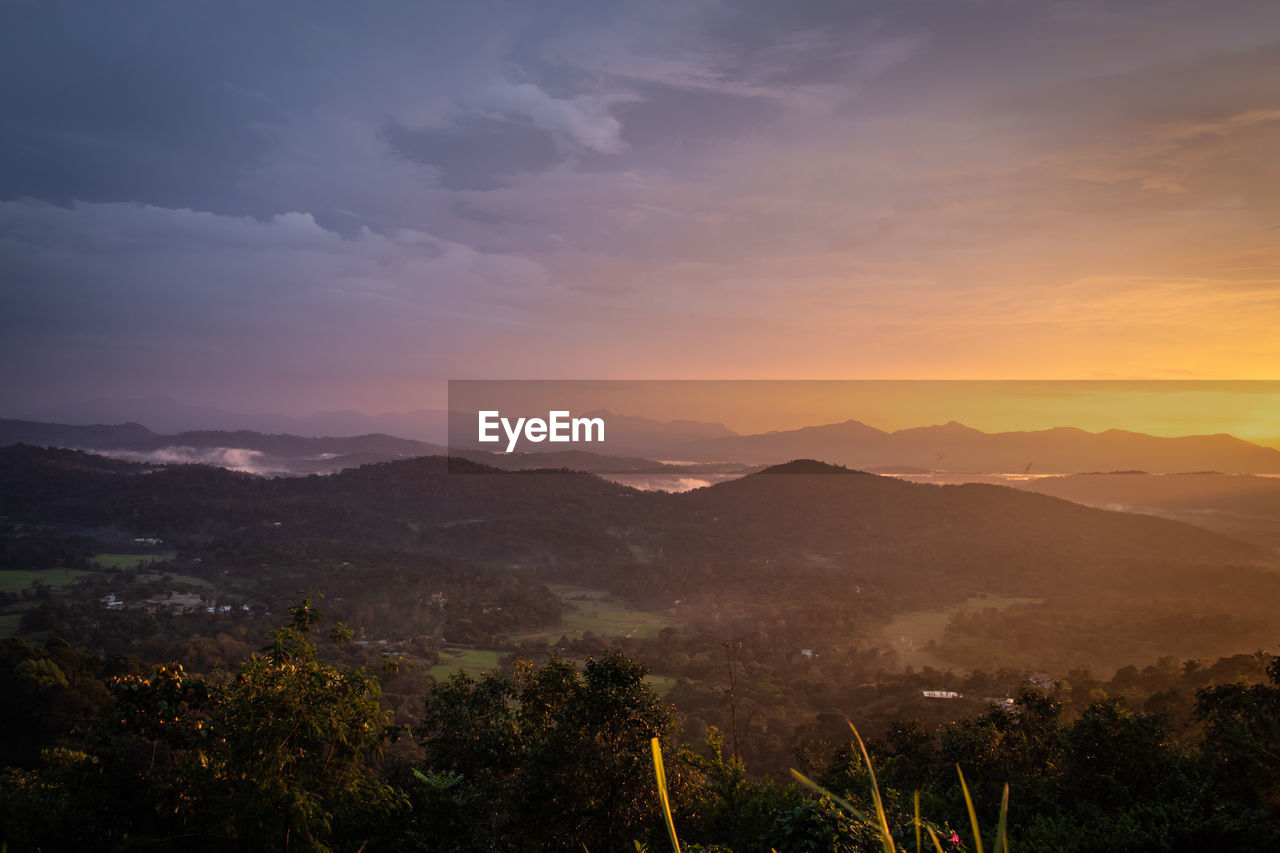 Mountains range misty shadow with dramatic colorful sunset sky at dusk from flat angle