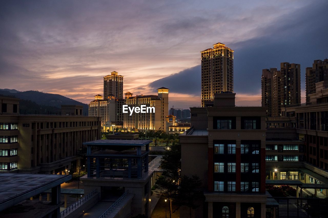 Modern buildings in city against sky at sunset