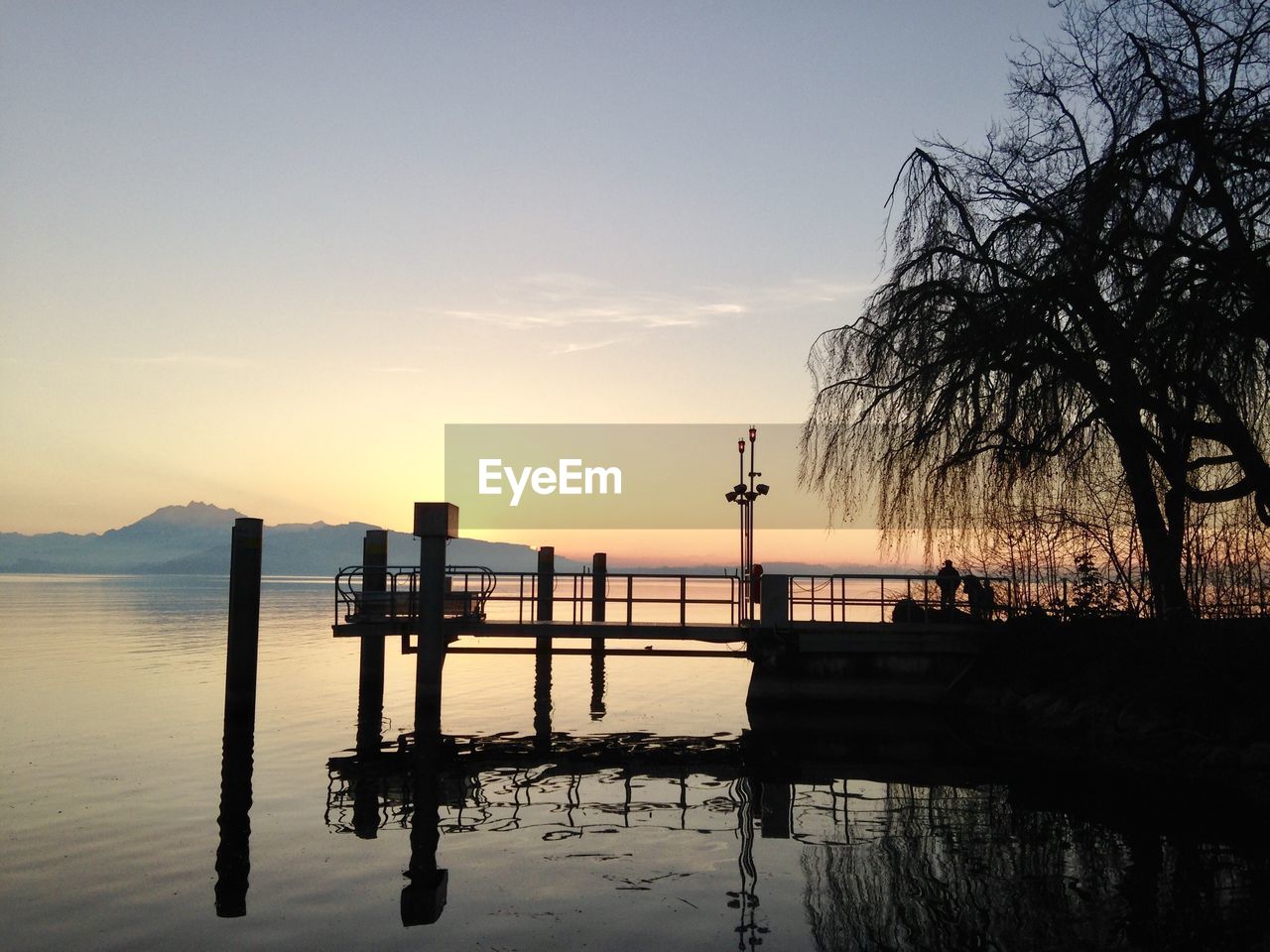 Silhouette pier on lake against sky during sunset