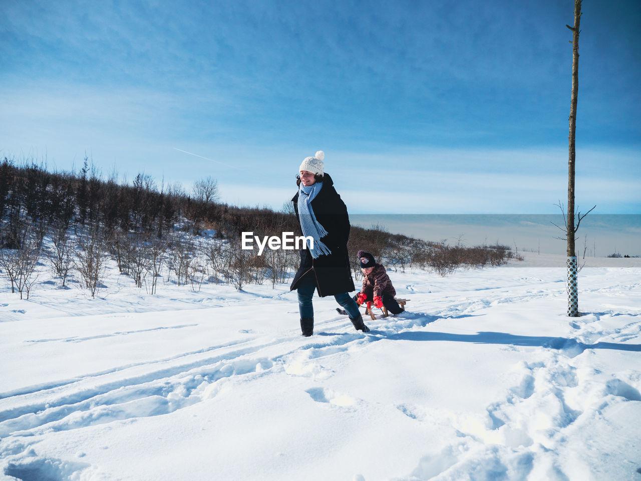WOMAN WITH UMBRELLA ON SNOW COVERED FIELD