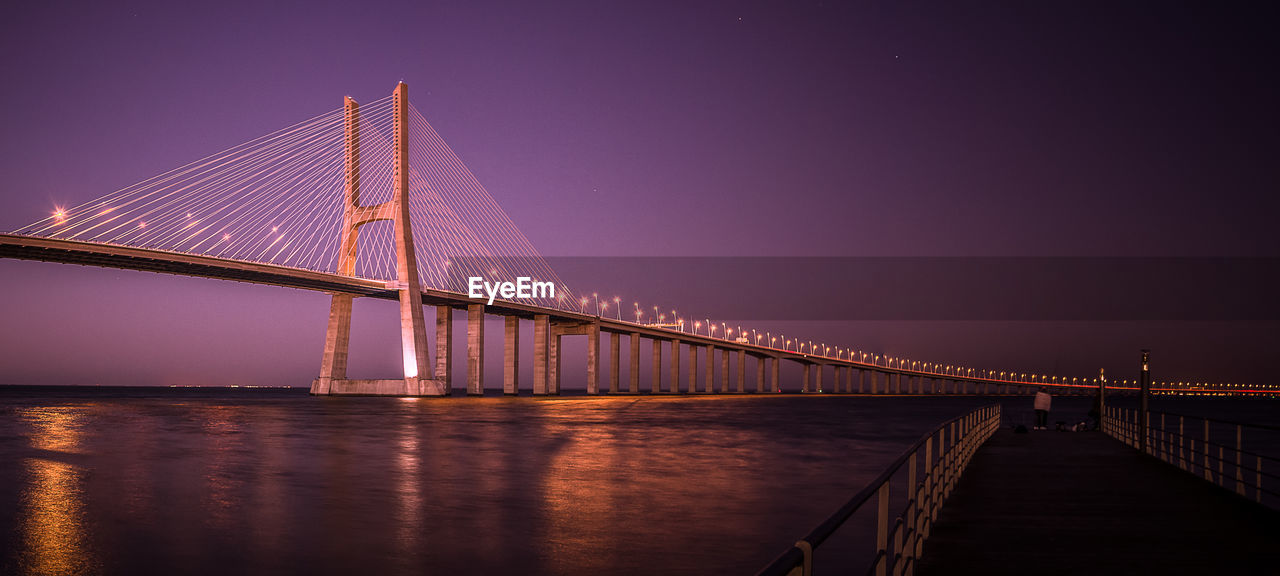 Low angle view of vasco da gama bridge over river against clear sky at dusk