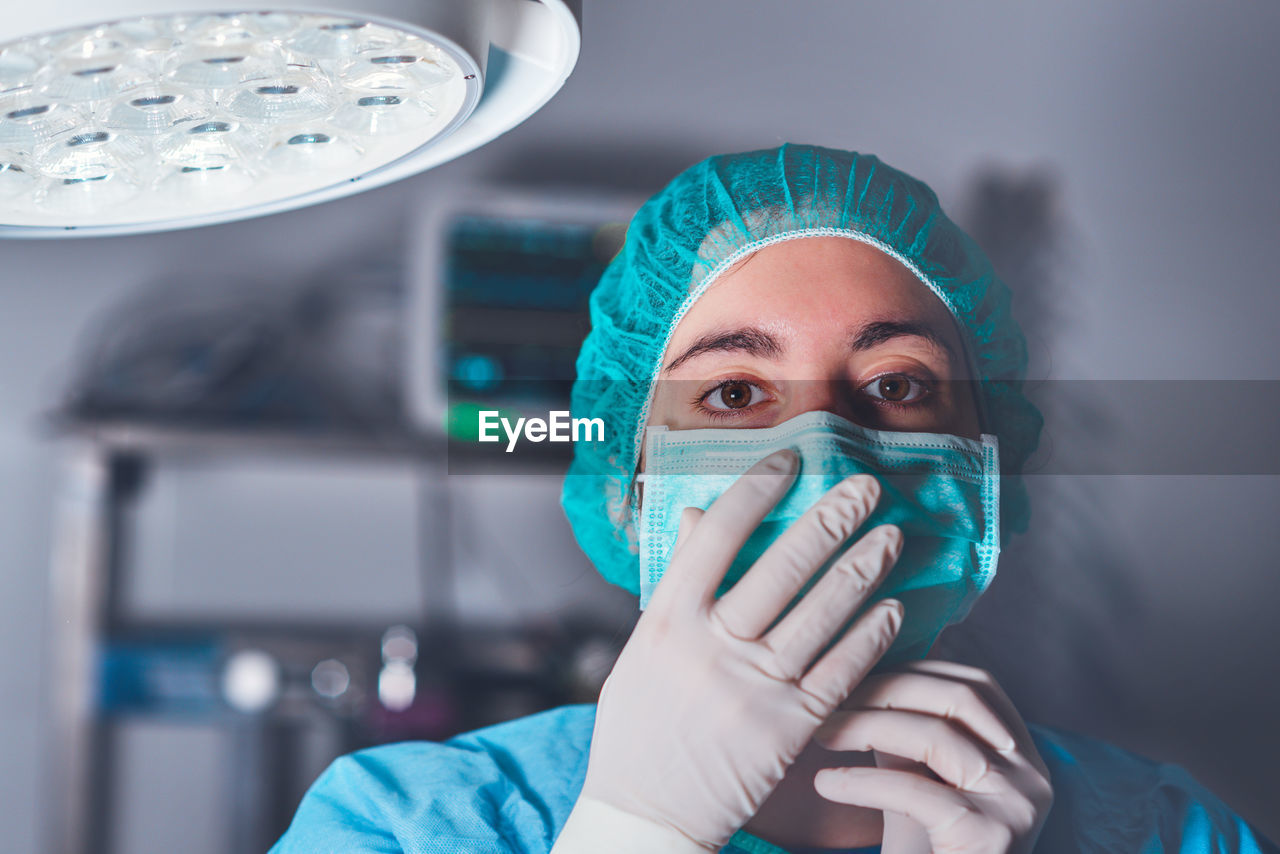 Adult woman in medical mask and hat looking at camera before performing surgery in hospital