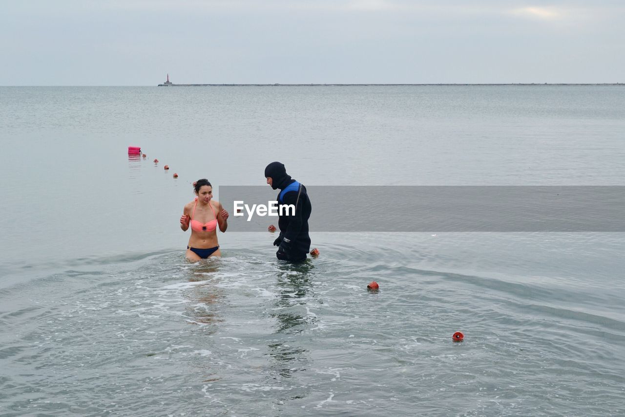 PEOPLE ENJOYING IN SEA AGAINST SKY