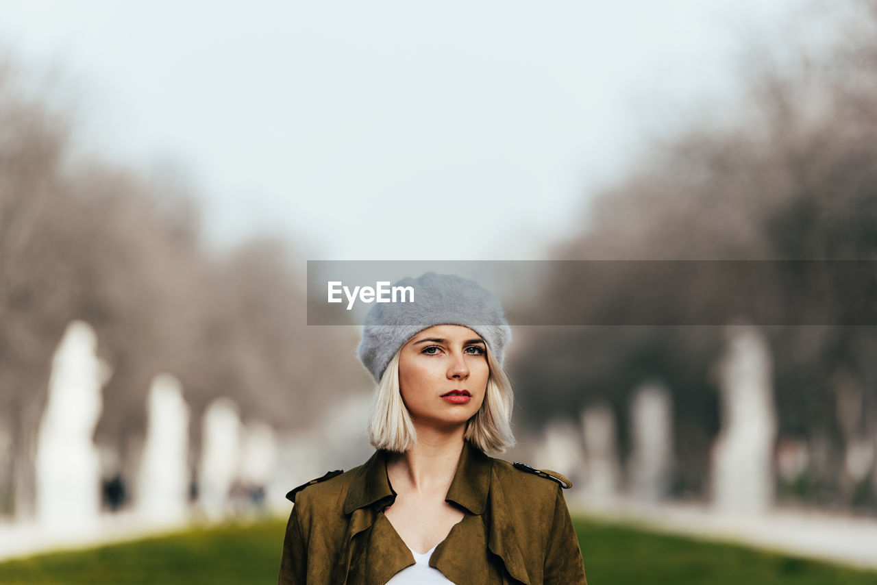 PORTRAIT OF BEAUTIFUL WOMAN STANDING AGAINST BLURRED BACKGROUND