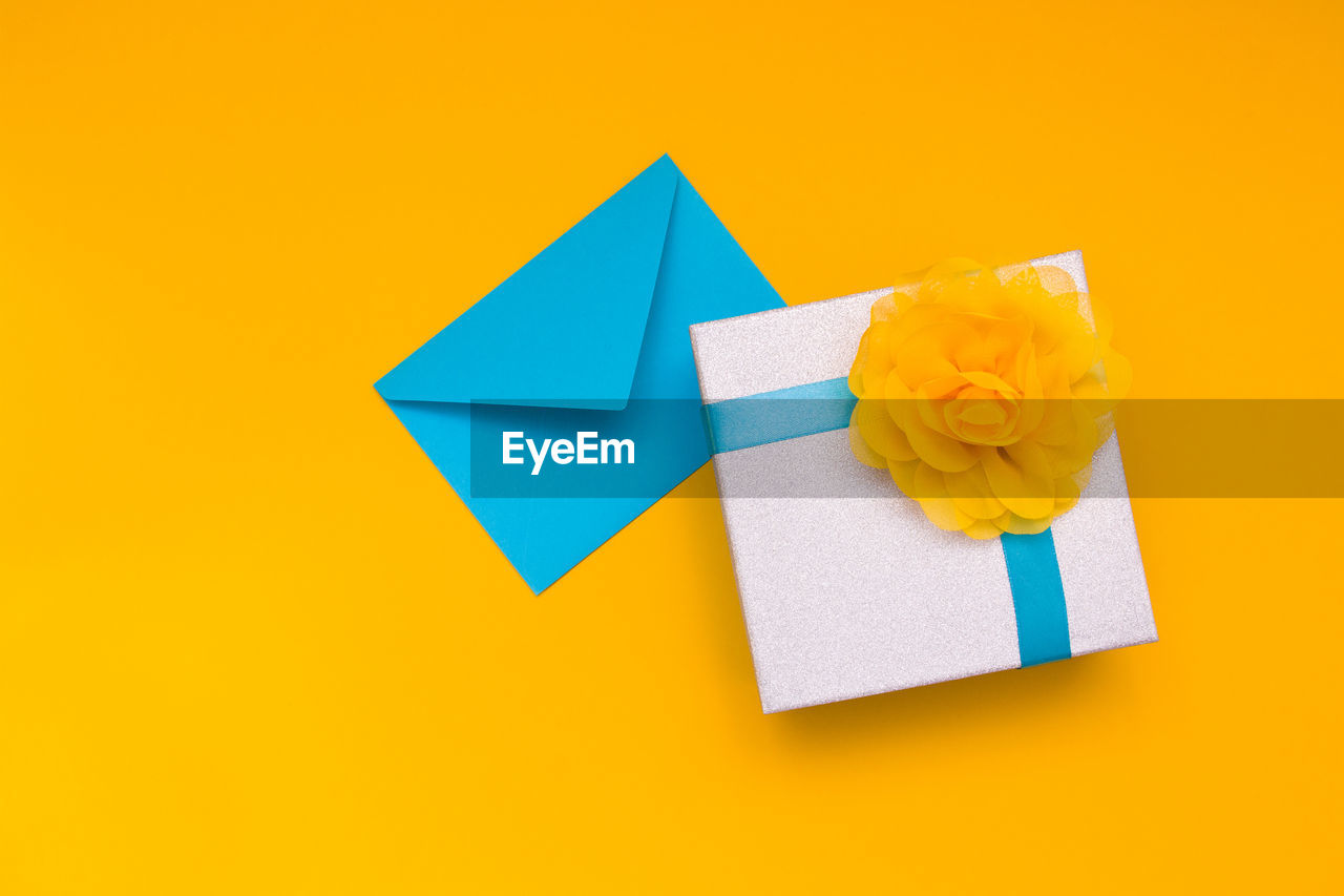 High angle view of box with envelop over yellow background