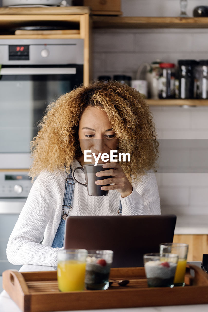 Young woman using phone while sitting on table