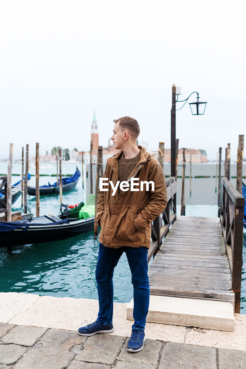 Young blond guy in a brown jacket in middle of streets of venice