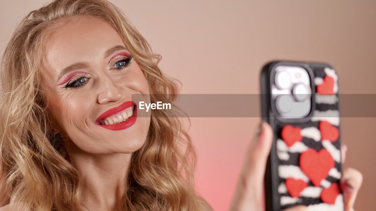 portrait of young woman using mobile phone against white background