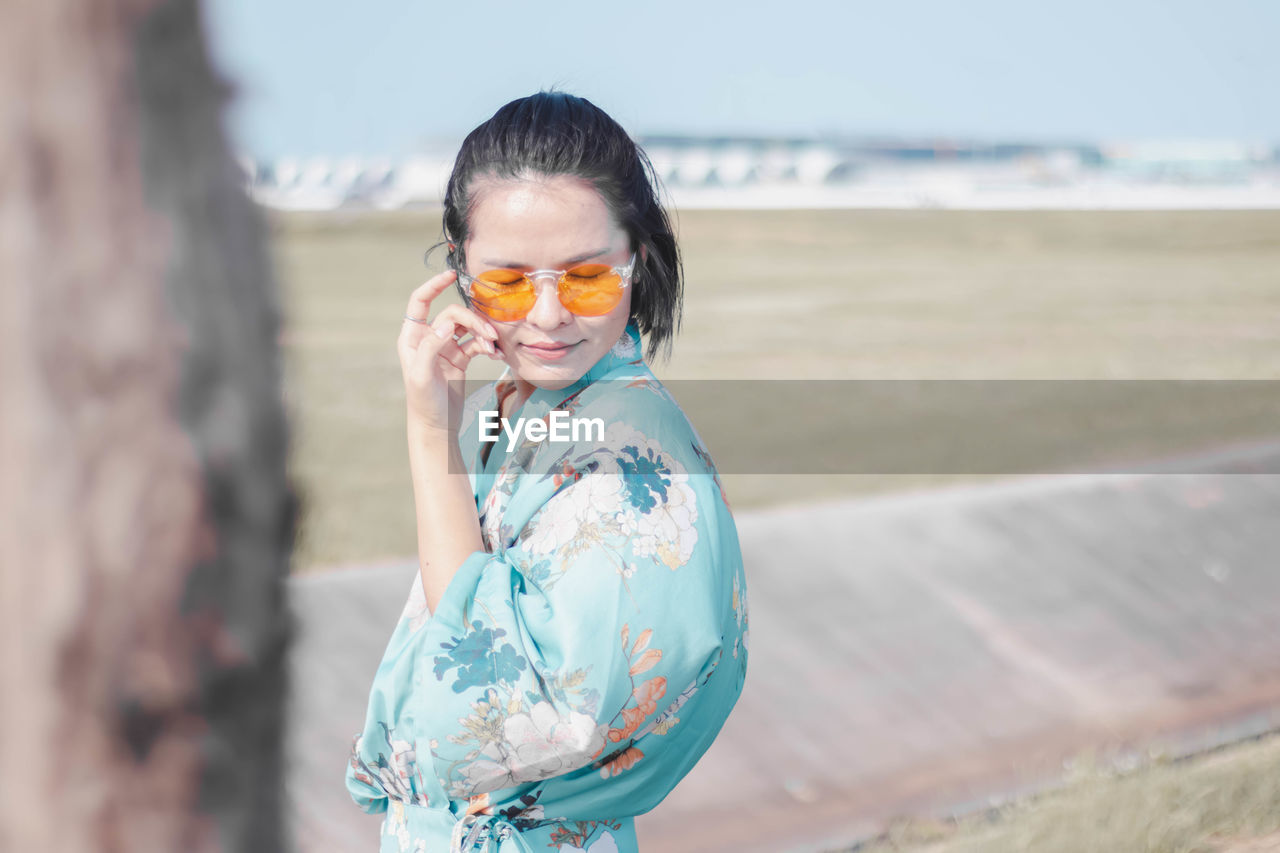 Woman wearing sunglasses while standing on land