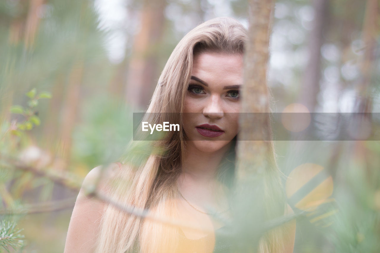 Portrait of young woman against trees