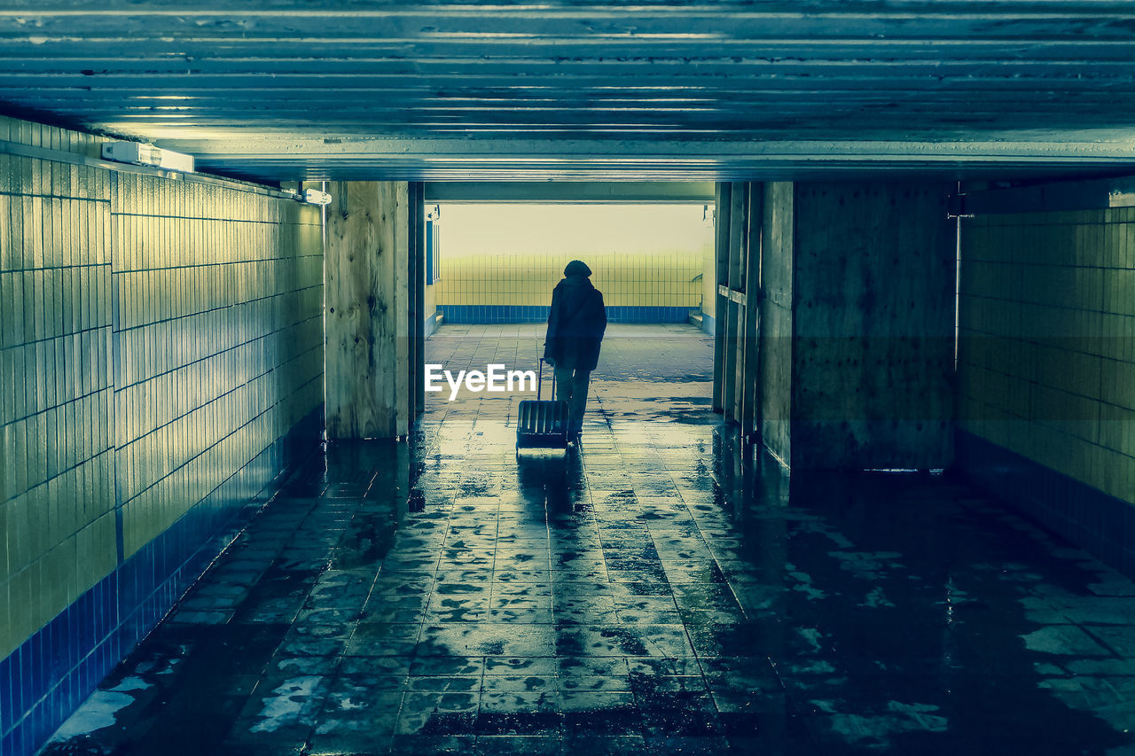 Rear view of man with luggage in abandoned building