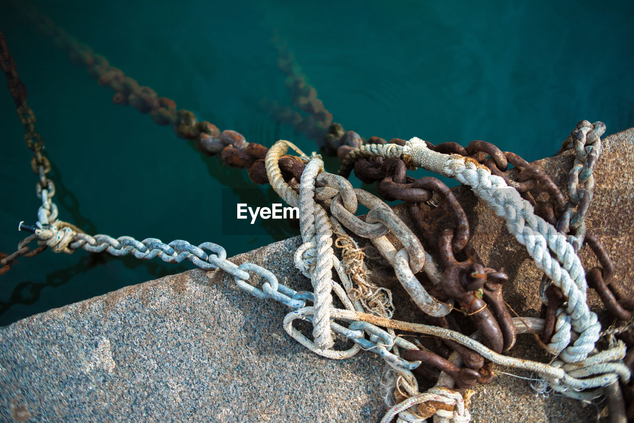 High angle view of ropes and chains on pier at harbor
