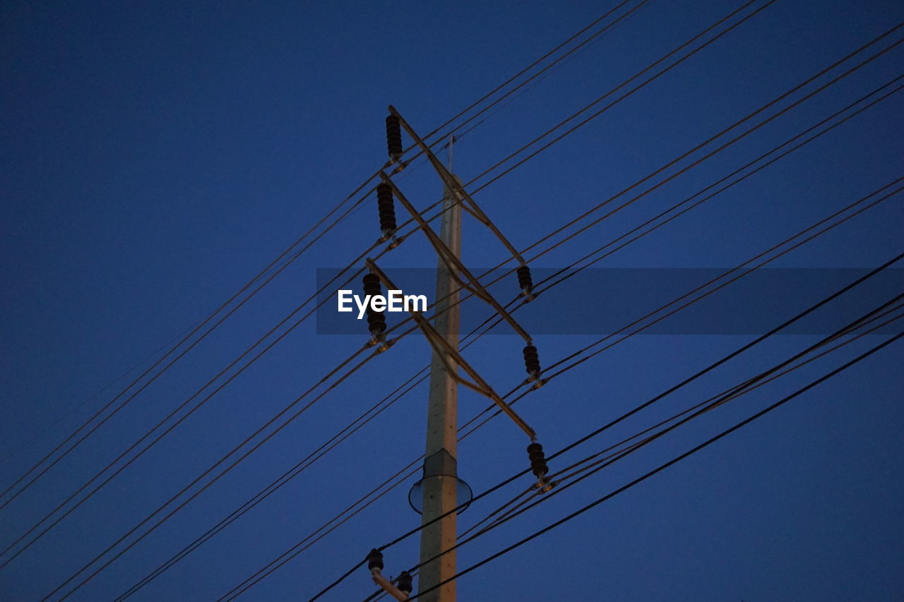 Low angle view of electricity pylon against blue sky