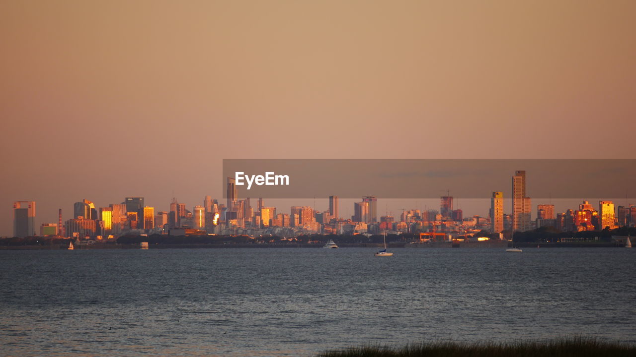 Sea by buildings against clear sky