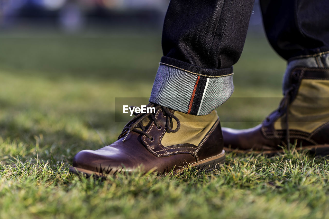 Low section of man wearing shoes on grass