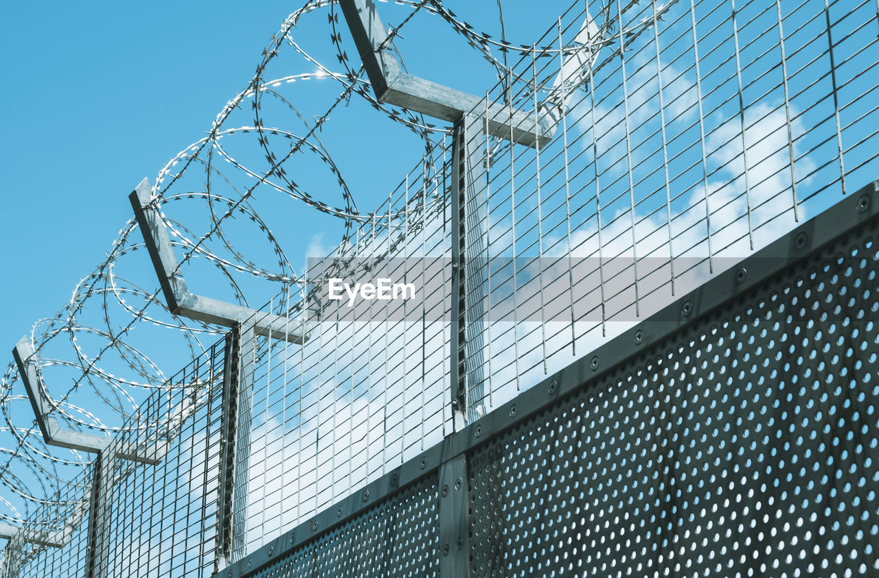 Metal fence against clouds and blue sky.