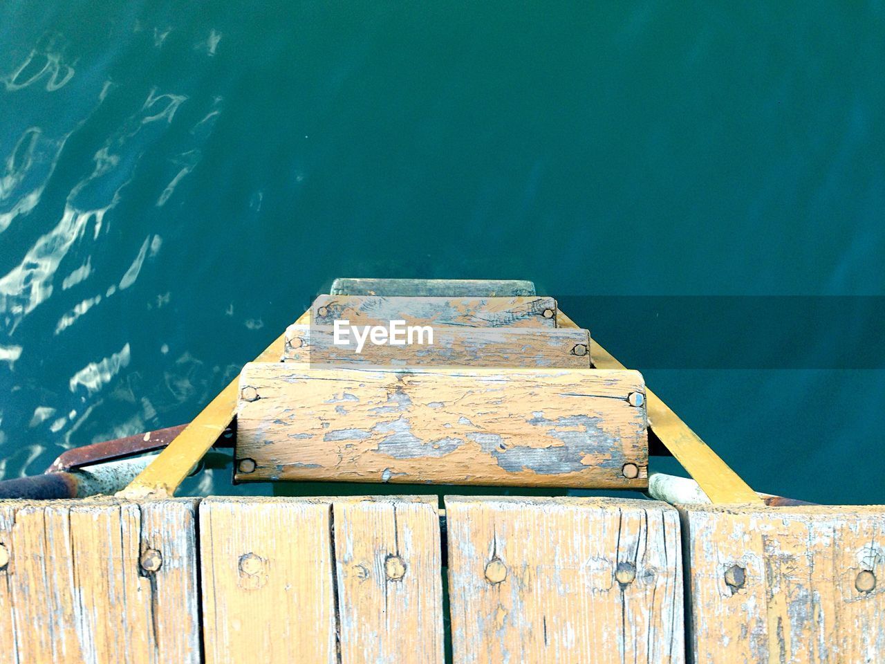 Directly above shot of wooden ladder on pier at lake