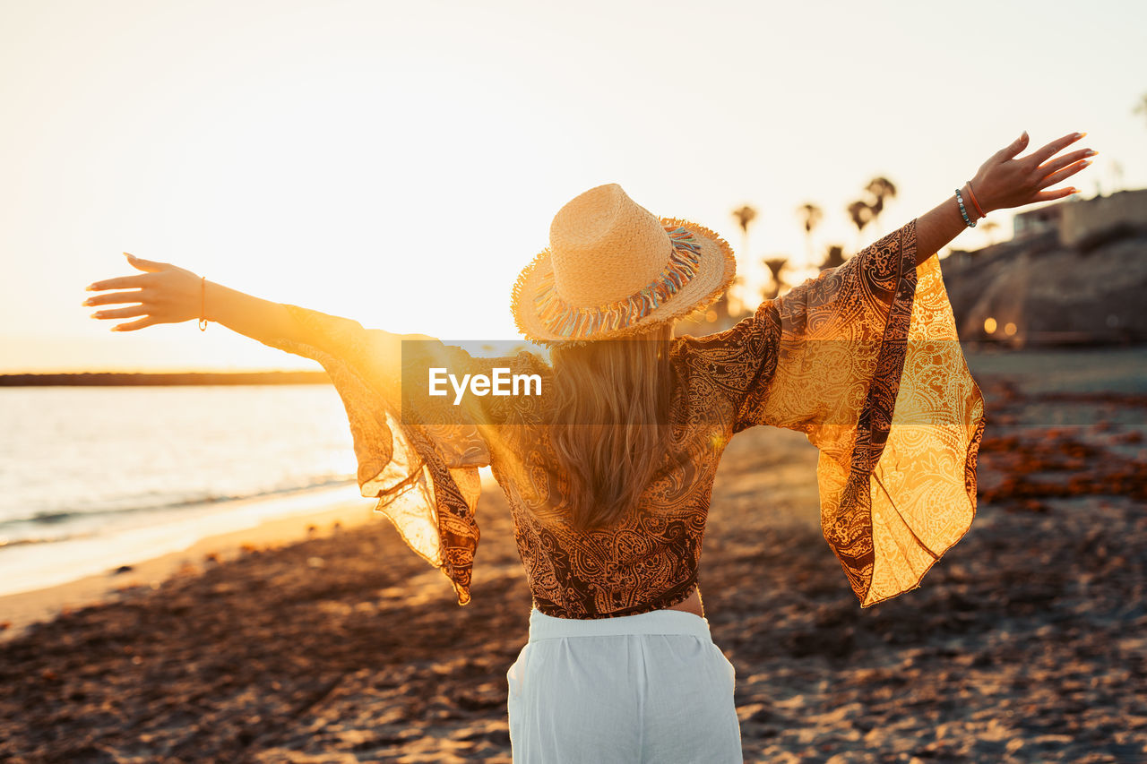 rear view of woman standing at beach against sky