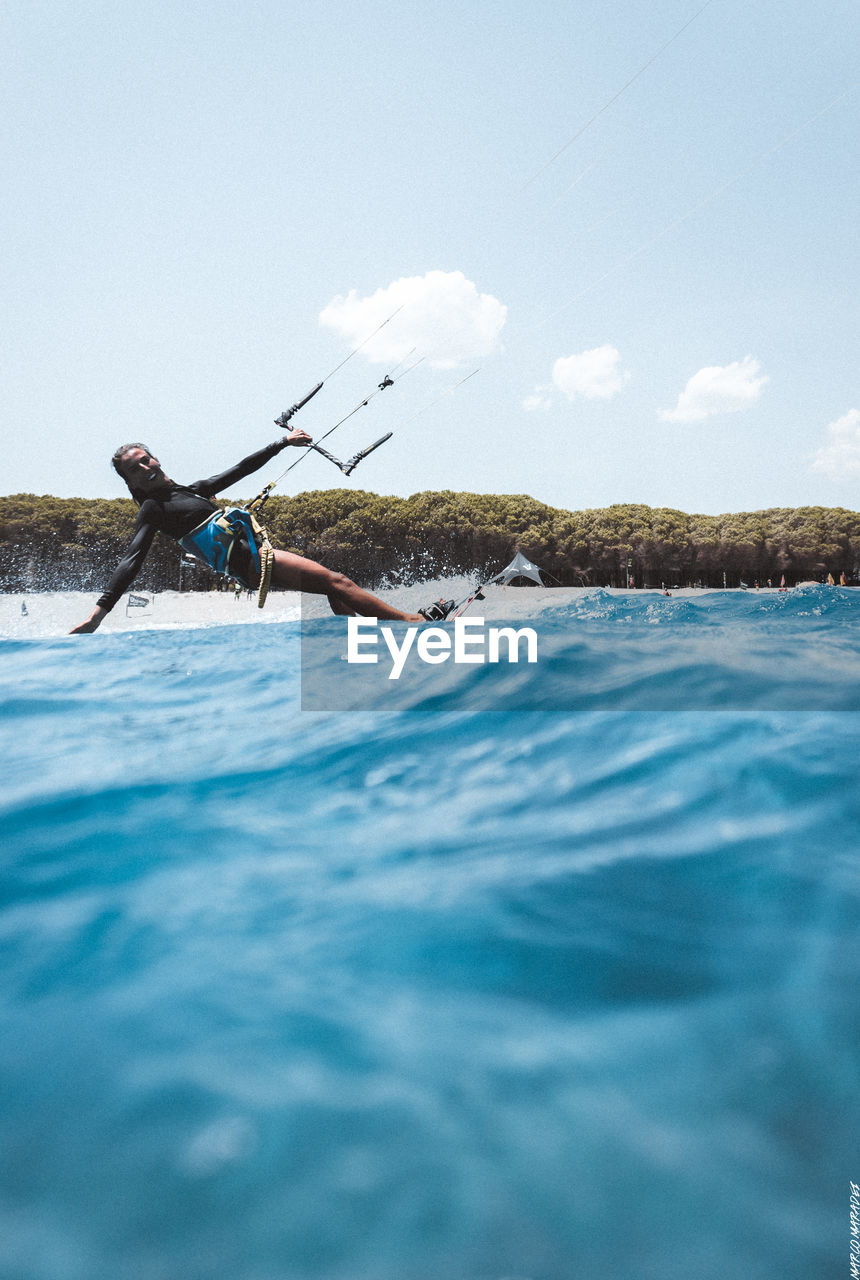 Portrait of woman kiteboarding on sea against sky