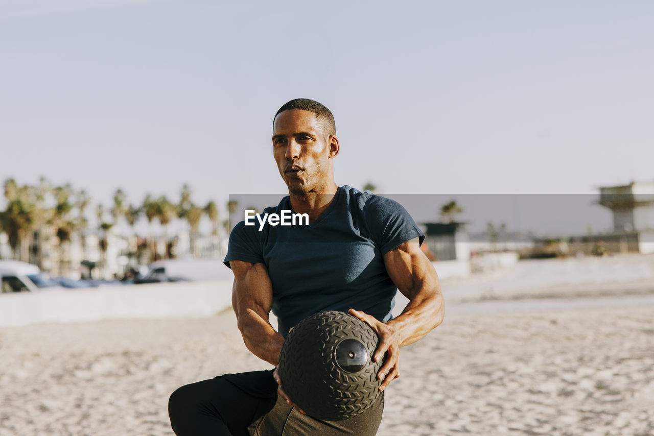 Mature man exercising with medicine ball on beach