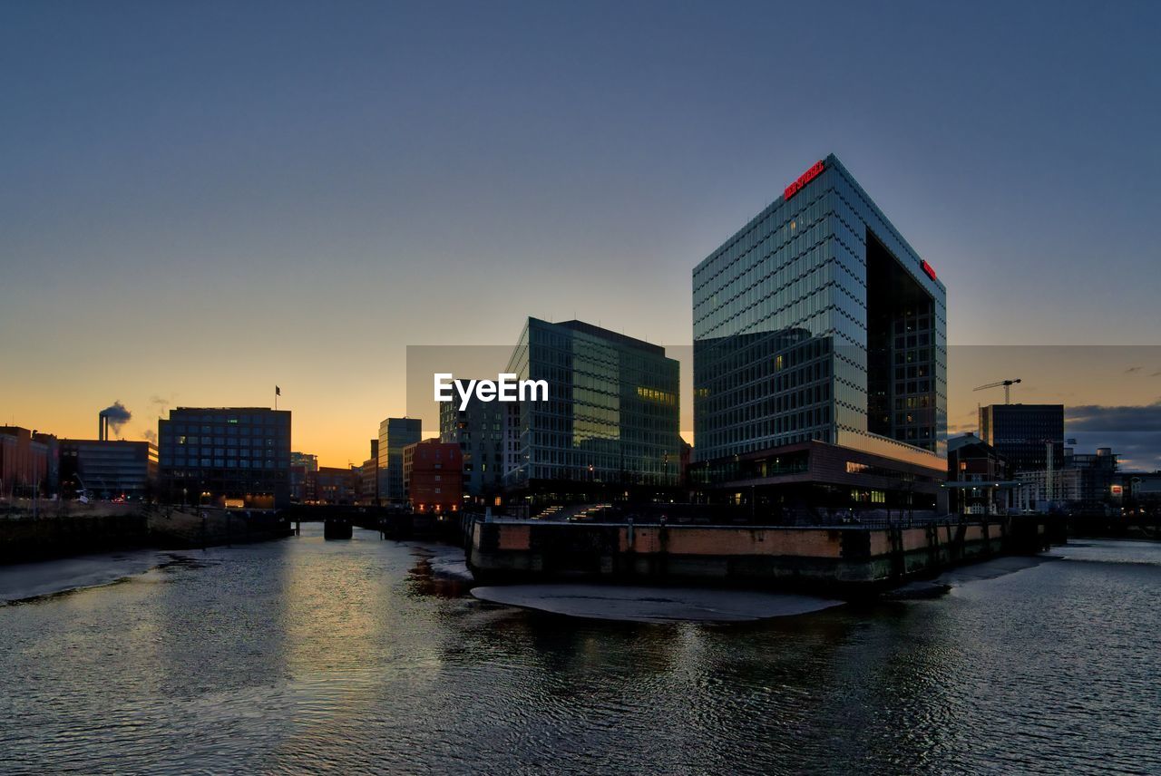 VIEW OF RIVER AND BUILDINGS AGAINST CLEAR SKY