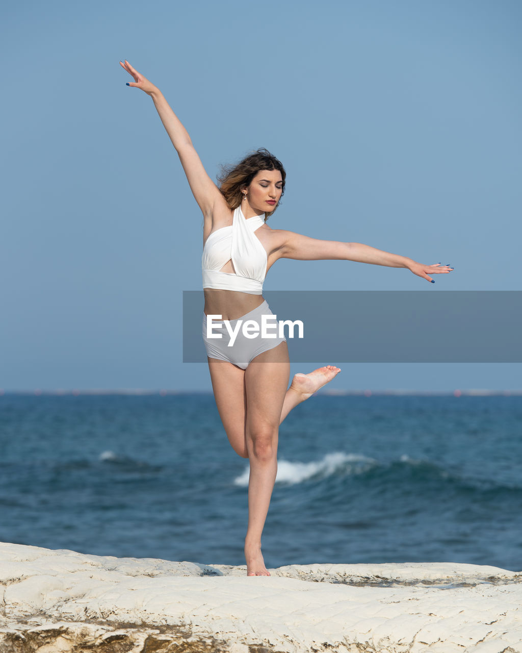 Full length of young woman at beach against clear sky