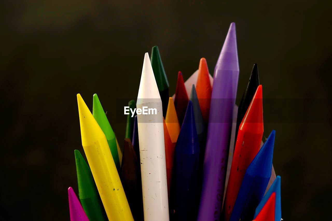 Close-up of multi colored crayons against black background