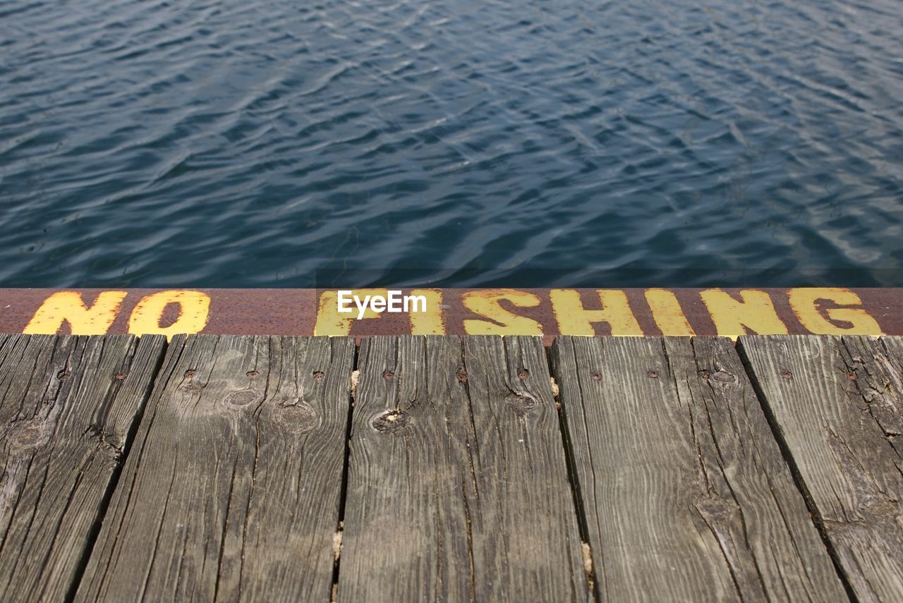 HIGH ANGLE VIEW OF TEXT ON WOODEN POST AT PIER