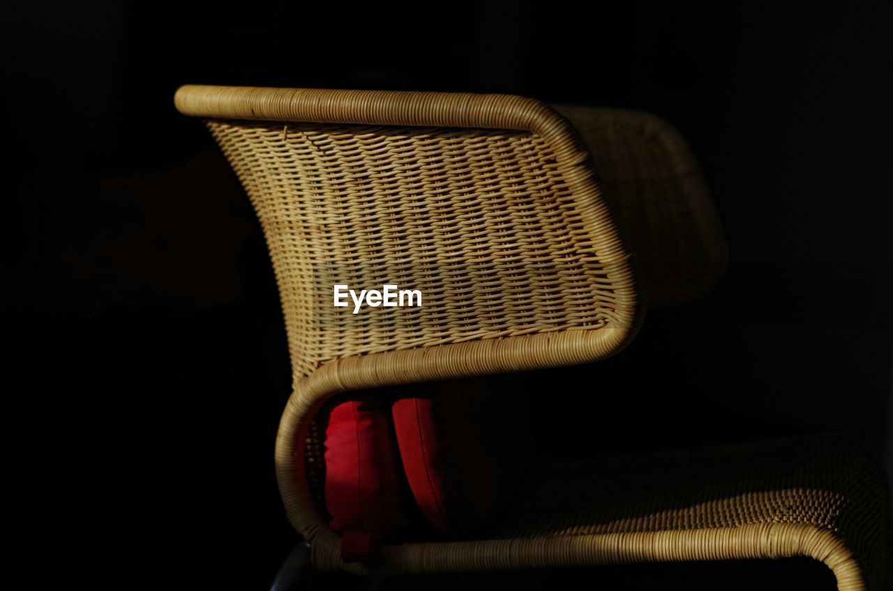 Close-up of wicker chair against black background