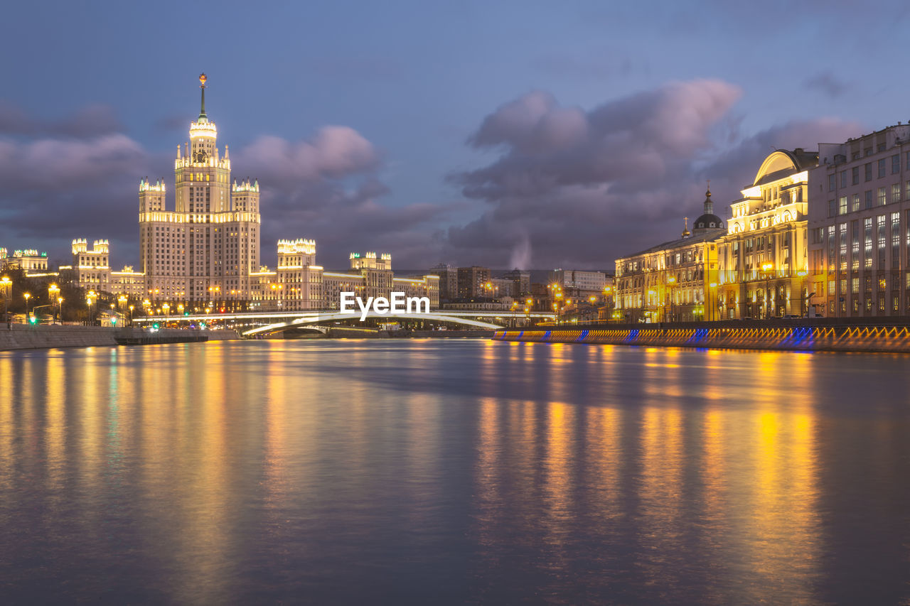 ILLUMINATED CITY BUILDINGS AT WATERFRONT