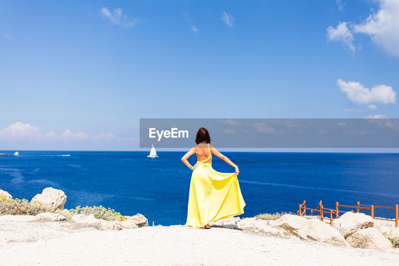 Rear view of woman on beach against sky