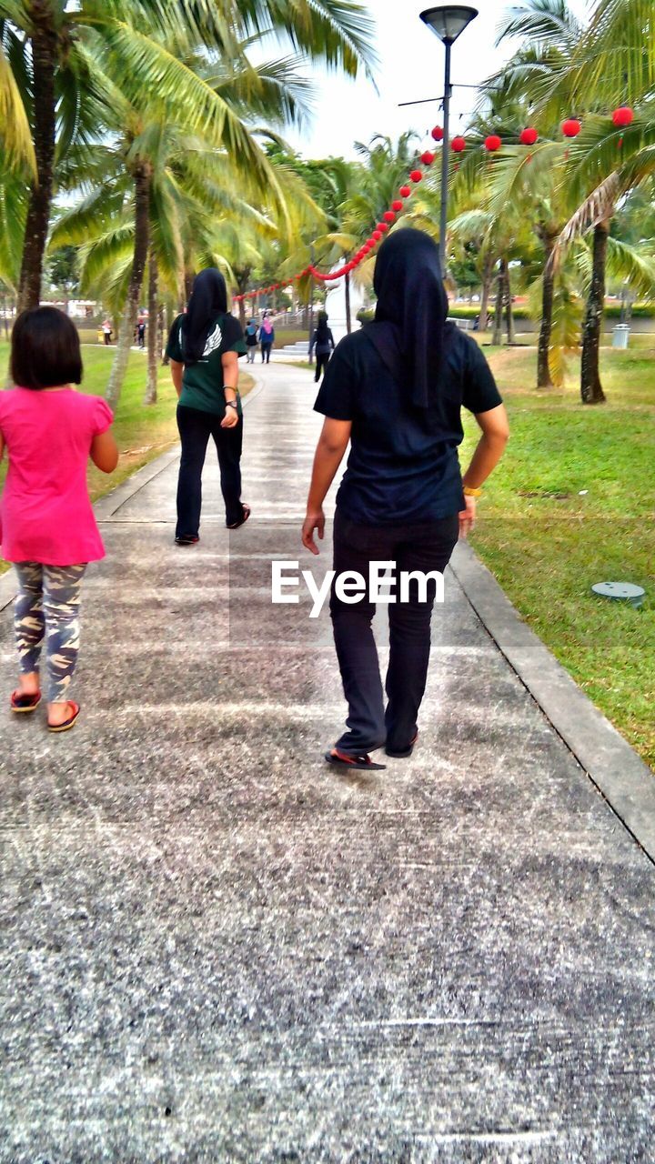 WOMAN STANDING ON FOOTPATH IN PARK