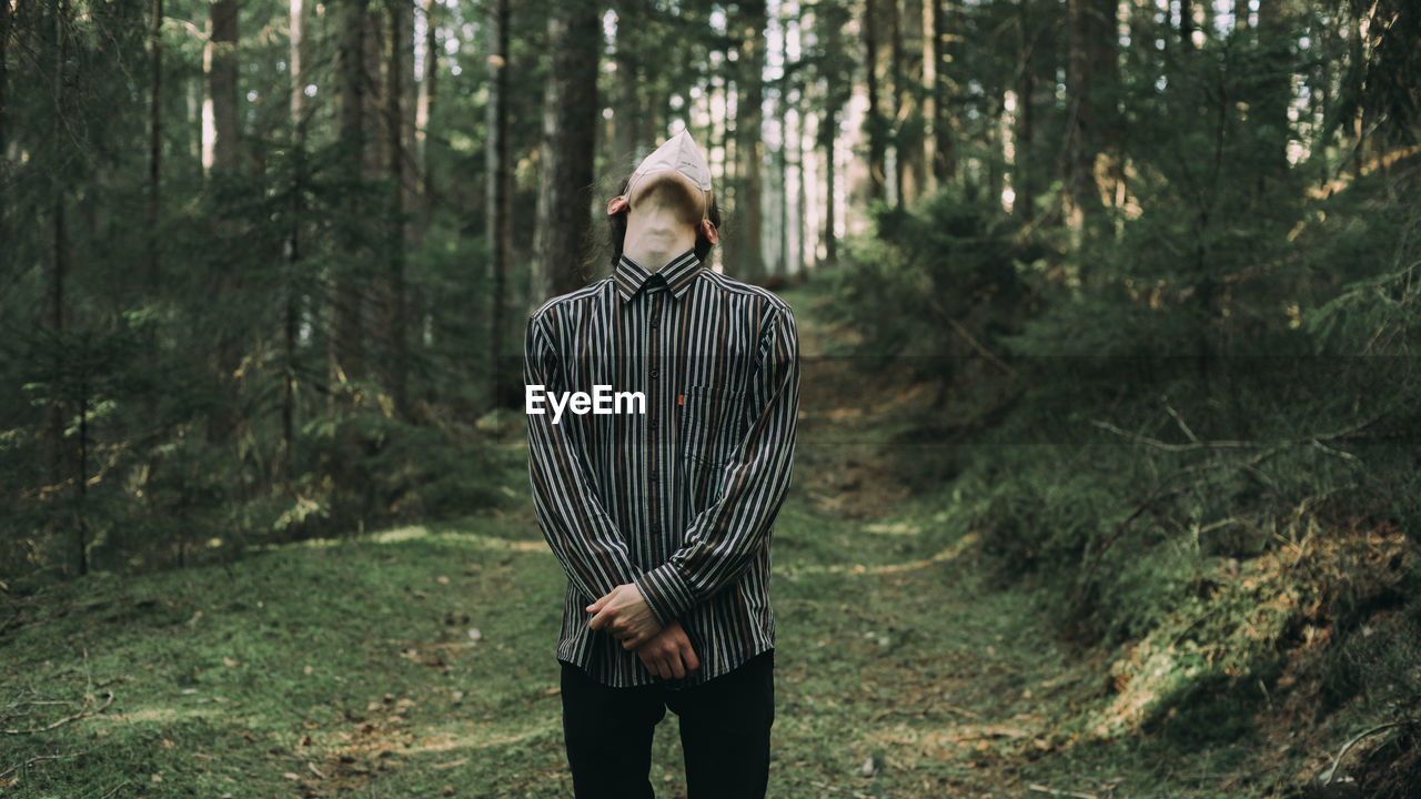 Full length of young man standing in forest with mask on 