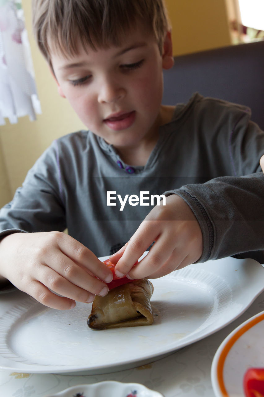 Boy preparing beef kebab in kitchen