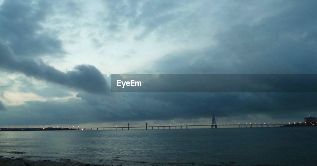 SCENIC VIEW OF BRIDGE OVER SEA AGAINST DRAMATIC SKY