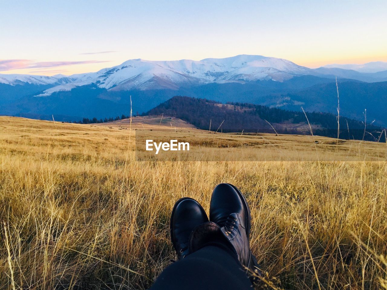 Low section of person standing on mountain against sky