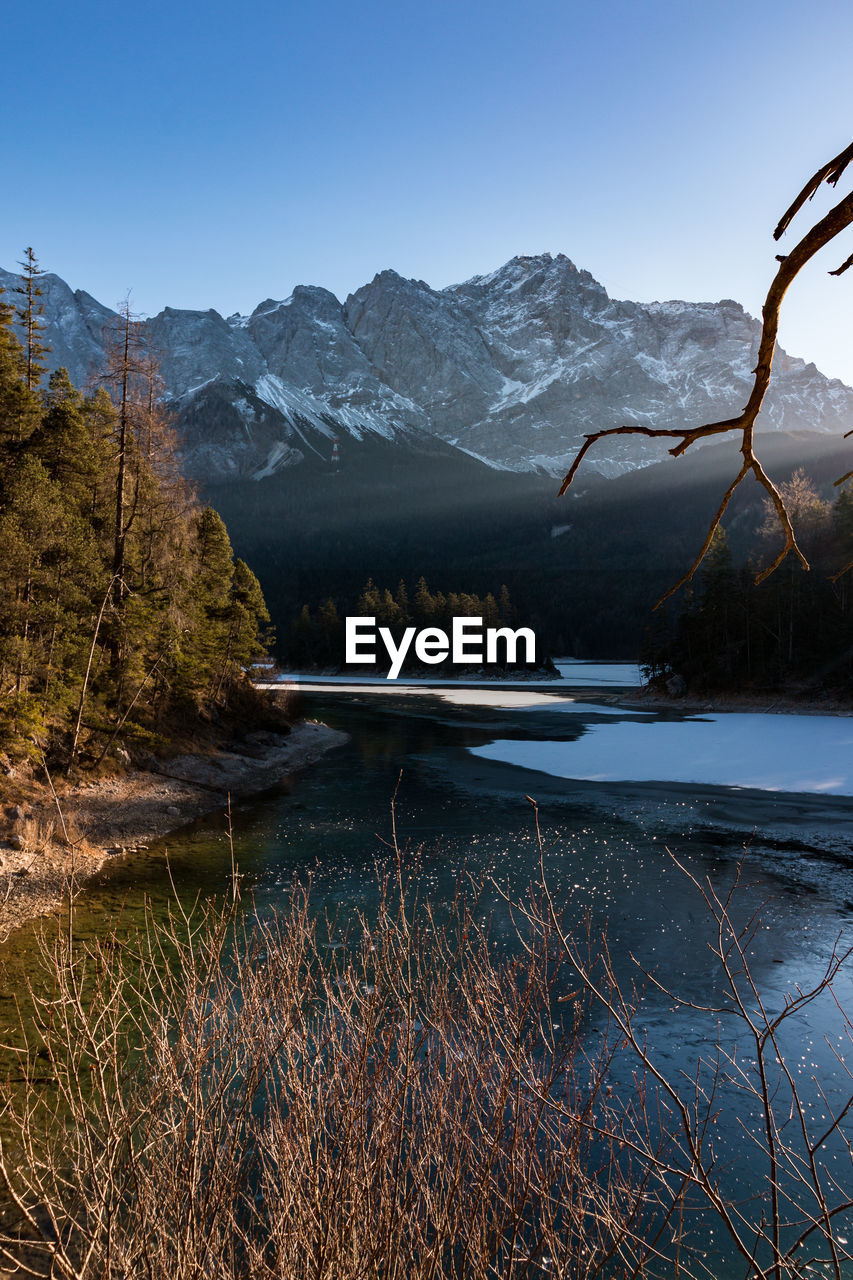 Scenic view of lake by mountains against clear sky