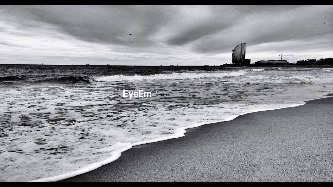 VIEW OF SEA AGAINST CLOUDY SKY IN CITY