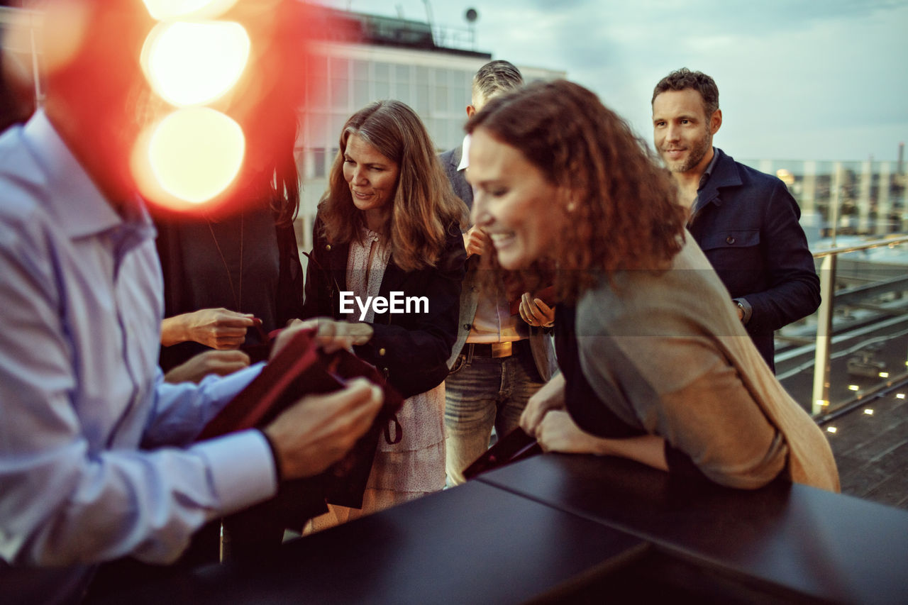 Business people discussing over gifts during office party on terrace