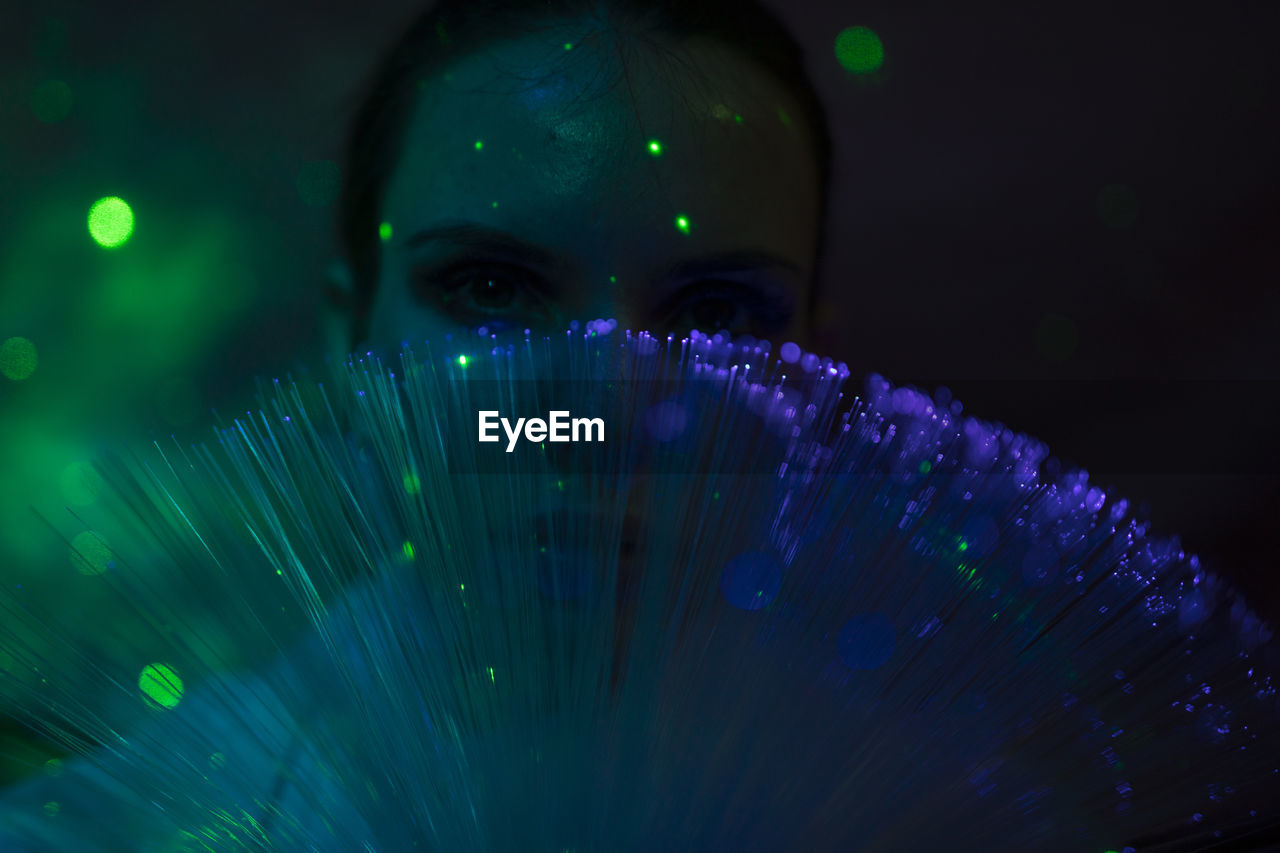 Portrait of beautiful young woman against illuminated background