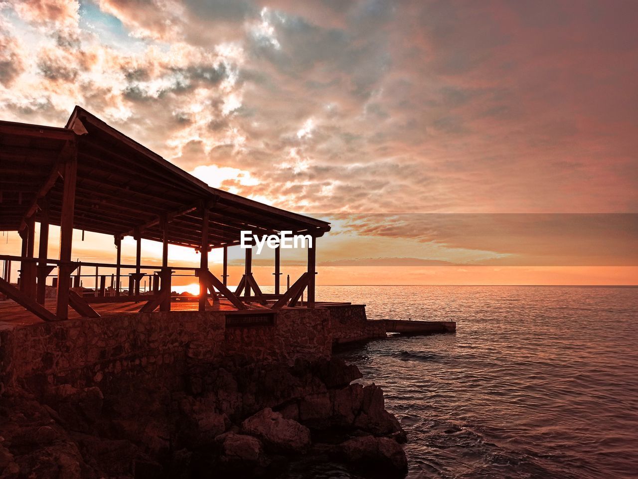 GAZEBO ON BEACH AGAINST SKY DURING SUNSET