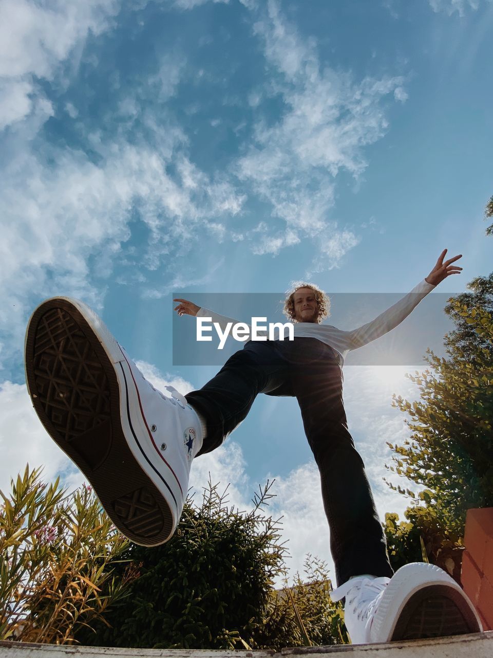 Low angle view of man with arms raised against sky