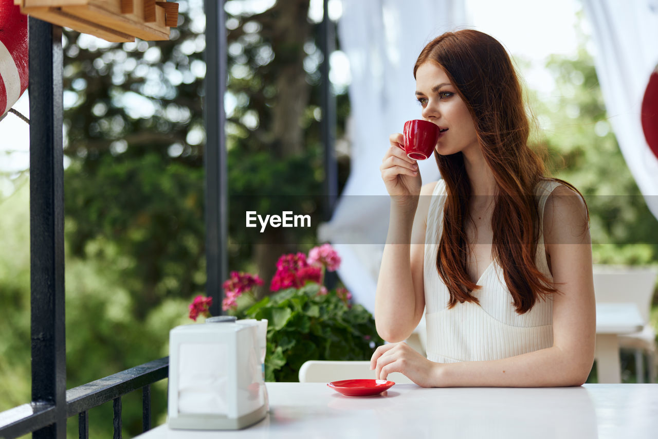 young woman using mobile phone while sitting in cafe