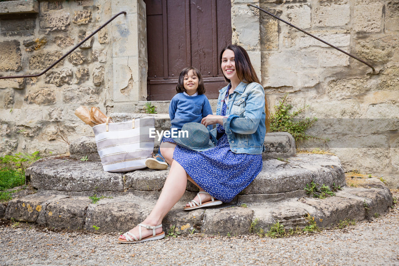 Mother and little handsome baby boy sitting on ancient stone stairs