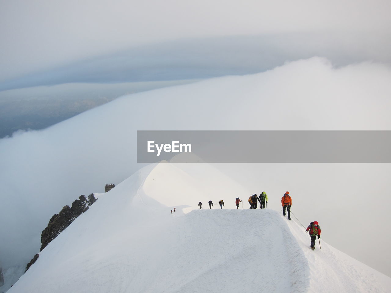 People on snow covered mountain against cloudy sky