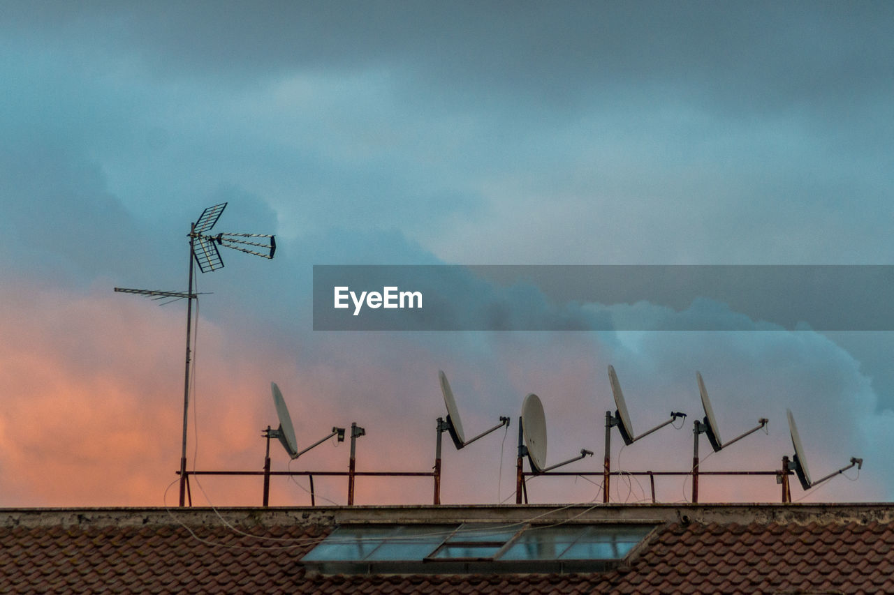 LOW ANGLE VIEW OF WIND TURBINES ON ROOF AGAINST BUILDING