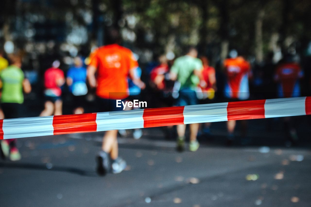 Cordon tape on road with people running in background during marathon